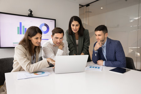 Marketing agency professionals meeting at laptop for teamwork in office boardroom, analyzing...
