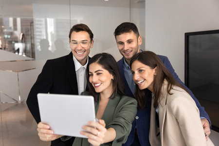 Team of millennial business professional colleagues taking staff selfie portrait on digital tablet for company blog on social media, using gadget, enjoying modern technology, leisure on work breakの写真素材