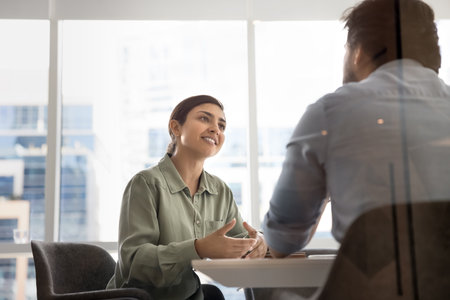 Professional consultation. Smiling young female advisor agent broker meet with client at modern office hold successful negotiations convince customer about benefits of loan insurance sales agreementの写真素材