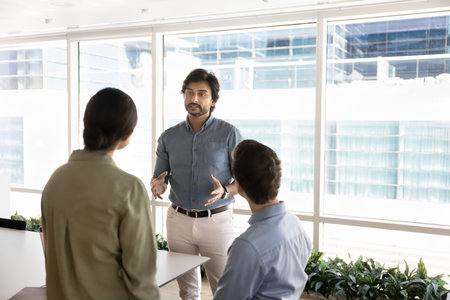 Diversity and mentorship. Experienced mature businessman coach mentor engage young multiethnic colleagues interns in thoughtful discussion at office workplace guide trainees on business best practicesの写真素材