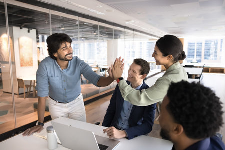 Celebrating success. Two happy diverse entrepreneurs colleagues join hands in high five on work meeting of multiethnic marketing research group software development team enjoy unity creative solutionの写真素材
