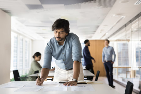 Working with information. Concentrated mid aged man project manager data scientist business analyst work with statistics in paper documents correct mistakes in sales report prepare financial forecastsの写真素材