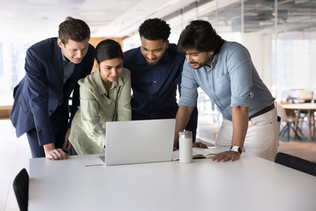 Uniting talents for success. Diverse multicultural businesspeople team interact with notebook at modern office workplace develop joint creative project engaged in professional discussion cooperationの写真素材