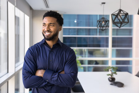 Modern businessman. Proud smiling Black gen z man entrepreneur startup developer creative professional look at window in office boardroom think on successful business solution enjoy career. Copy spaceの写真素材