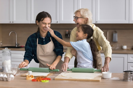 Family cooking is easy and fun. Overjoyed happy old lady adult daughter tween granddaughter joke by...