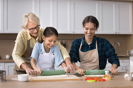 Family baking traditions. Three friendly female generations older grandma millennial mum preteen...