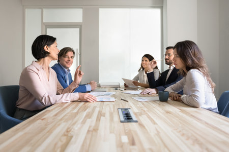 Intergenerational business collaboration. Mature experienced female corporate team member offer strategic idea share insight expertise at department staff conference brainstorm session in meeting roomの写真素材