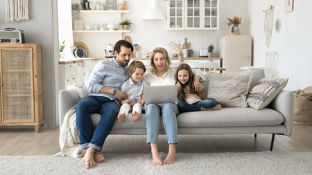 Shared screen time. Happy full family of mid aged parents with little kids junior school age...