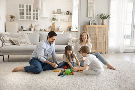 Family playtime. Loving parents sit with young daughter son on warm carpet in modern studio flat interior playing colorful toys cubes guide children in creative game that develop fantasy imaginationの写真素材