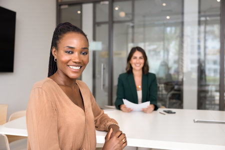 Positive beautiful young African American job candidate posing for portrait at table of recruiter on...