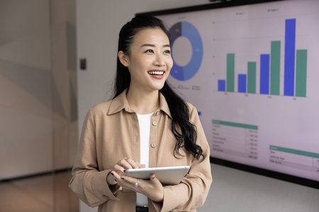 Fintech and vision of success. Confident young woman financial expert project manager hold digital tablet at office workplace look away plan future opportunities inspired by successful business growthの写真素材