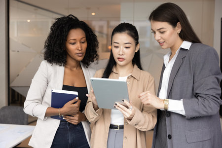 Informal idea sharing and casual teamwork. Three beautiful young women coworkers from diverse ethnic...