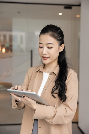 Tech savvy professional. Busy young female corporate executive manager use digital pad pc in office workspace for business planning analyzing fintech reports strategies reviewing trends via online appの写真素材