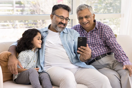 Little boy spend time with aged grandfather and old great-grandpa using smartphone together, enjoy...