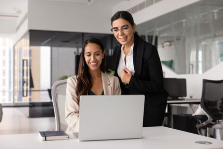 Positive young 30s and old 60s teammates engage in productive teamwork using laptop in modern office, working on project, planning marketing strategy feel satisfied and contented with workflow resultsの写真素材