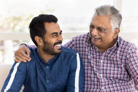 Young Indian man spends priceless time with older grandfather, laughing, enjoying funny talk,...