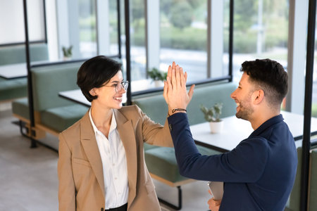Multiethnic colleagues, business partners exchanging high five, greeting or congratulating with...
