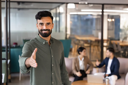 Portrait of Middle Eastern businessman extending hand for handshake, greeting client of job applicant, representing business agreement, partnership, recruitment, human resources and customer servicesの写真素材