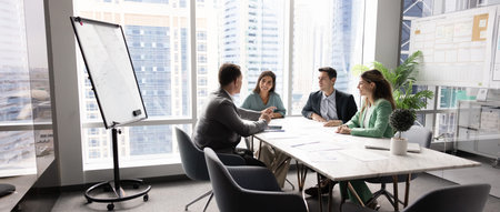 Diverse corporate team holding open discussion by conference table collaborating on shared project...