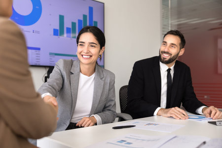 Smiling professional businesspeople shaking hands at conference table, begin or finalizing seminar,...