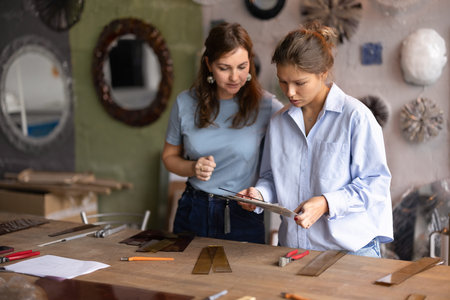 Artisans collaborating on glasswork project, discussing design, planning creative workflow at...