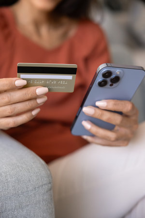Close up hands holding mobile phone and credit card. Young female making secure online payments,...