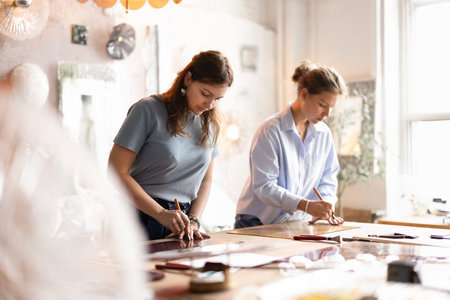 Workflow of craftswomen in creative studio, cutting glass sheets for upcoming project, working on...