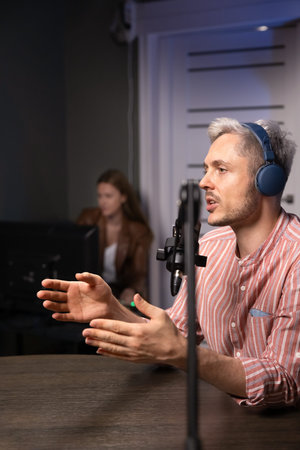 Male podcaster in headphones speaking with channel guest, discussing topics, sharing personal...
