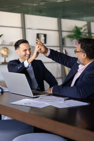Happy businessmen, team members closing deal, giving high five, celebrating positive financial...