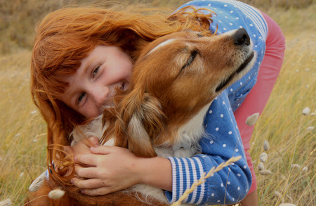 red headed girl hugging red haired dog の写真素材