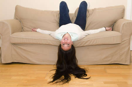 Young woman laughing while upside down in a chair