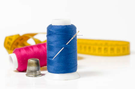 sewing utensils, thread, thimble, needle and meter on white background