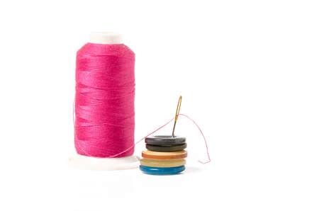 Pink thread with needle and buttons on white background
