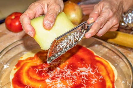 Hands on first plane using a grater, grate cheese for a pizzaの写真素材