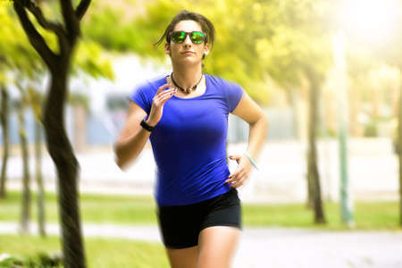 Woman running in the park with sunglassesの写真素材
