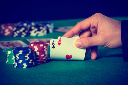 Closeup of poker player with two aces in pastel colors