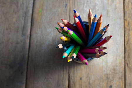 Colored pencils stuck in a can on old wood.の写真素材