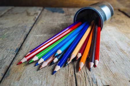 Colored pencils stuck in a can on old wood.の写真素材