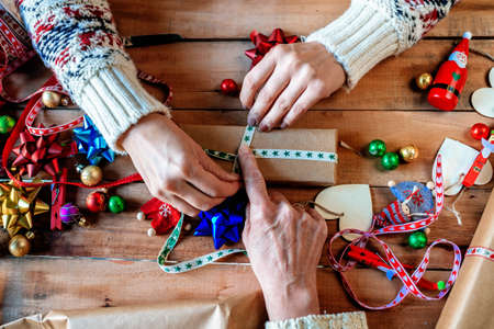 Close-up of hands of two women wrapping Christmas gifts.の写真素材