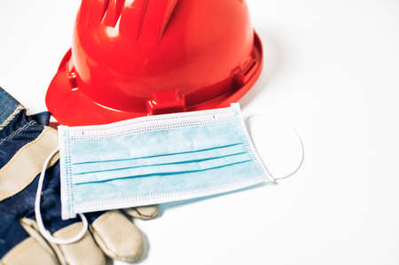 Worker's helmet and gloves next to antiviral mask on white background