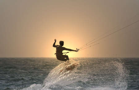 sunset kitesurfer flying over a waveの写真素材