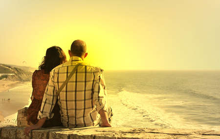 photo of a couple seated watch the sunsetの写真素材