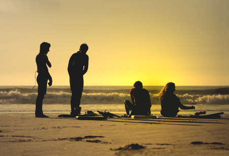 four bodyboarders in the beach at sunsetの写真素材