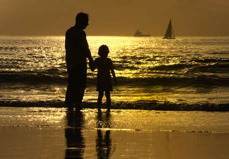 father and son at sunset in the beachの写真素材