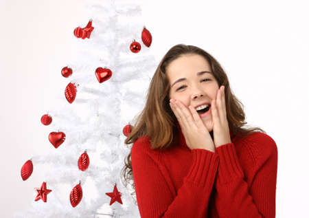 Beautiful young woman next to christmas tree on white backgroundの写真素材