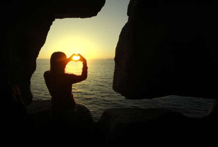 heart shape made with a girl hands at sunsetの写真素材