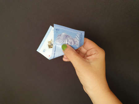 hand of a woman holding Malaysian money