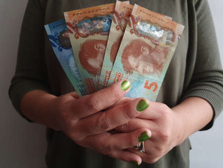 hands of a woman holding New Zealand money