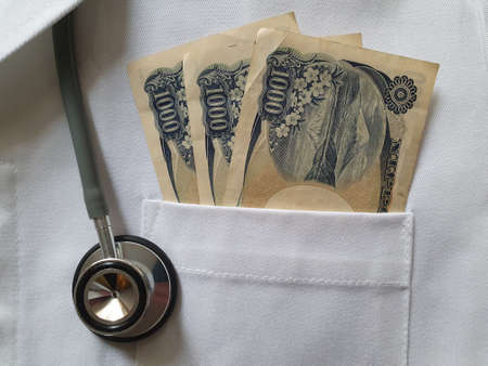 japanese money in the bag of a white fabric gown and stethoscopeの写真素材