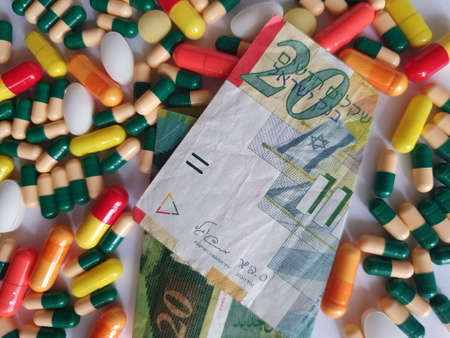Israeli banknote of twenty shekels, capsules and medicine pills